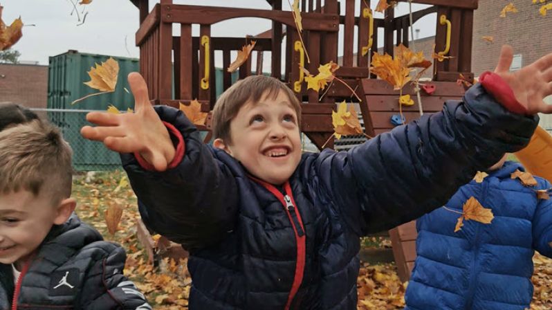 Small boys happily throwing autumn leaves into the air.